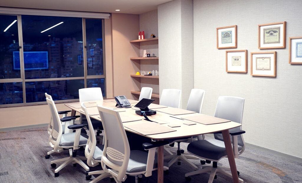 Nosotros 28 Sala de juntas moderna. Mesa de madera con sillas blancas y equipo de oficina para reuniones.